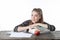 Girl student sitting on wood table with her hands on the books. Smiling Girl with apple, books, on wooden table.