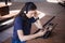 A girl student with a smartphone, sits at a laptop and listens carefully in headphones, learns foreign languages.