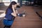 A girl student with a smartphone, sits at a laptop and listens carefully in headphones, learns foreign languages.