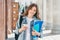 Girl student smiling against university and holds mobile phone in hands. Learning,