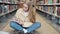Girl student using laptop hybrid learning sitting in university library.