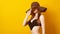 Girl in summer black hat and swimsuit. Black friday concept. Young sensual woman in swimwear, isolated over yellow. Seasonal