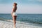 Girl in summer dress standing on a beach and looking to the sea