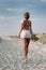 Girl in summer dress standing on a beach and looking to the sea