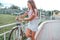 Girl in summer stands at bike, locks bike with cable. Picks up a password on the lock, against theft of a bicycle in the