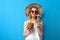 Girl in a sun hat and glasses drinks tropical cocktails made of pineapple and coconut and dreams on a blue isolated background, a