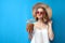 Girl in a sun hat and glasses drinks a tropical pineapple cocktail on a blue isolated background, a woman with an exotic drink is