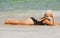 Girl sunbath near sea. Summer vacation on beach. Woman in black swimwear lying on sandbeach.