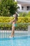 The girl sunbathes standing on edge of pool