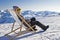 Girl sunbathing in a deckchair on the side of a ski slope