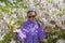 The girl in sunglasses against the background of the blossoming Shlippenbakh`s rhododendron in the park