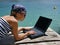 Girl with sunglasses and laptop on sea