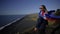 A girl in sunglasses with the national flag of Iceland stands near a cliff