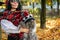 A girl in sunglasses with a scarf on her head holds a British cat in a hat with a pompom in her arms against