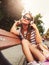 Girl with sunglasses sitting on a bench in the summer listening music over headphones