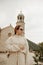 A girl in sunglasses and a white suit walks on the island. Travel, Montenegro. Boka island Church of Our Lady of the Rocks Kotor