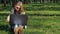 Girl on a sunny day in a park with a laptop. A teenage girl wearing sunglasses in nature. A teenage boy is sitting on the green gr