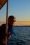 A girl at sunset stands on deck of the ship. Calm lake while traveling