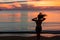 Girl at sunset stands near the sea raising hands freedom concept