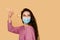 Girl with sushi in medical mask on yellow background. Young woman is holding sushi by chopsticks. Sushi delivery at