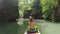 A girl is swimming in a sea kayak with oars among jungle