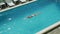 Girl swims in the outdoor pool at the hotel in a black swimsuit