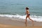 Girl in a swimsuit jogs along the sandy beach