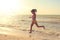 Girl in swimsuit runs along the shore of the sea. Toned image