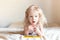 Girl in swimsuit sitting in a rubber ring on the bed imitating swimming at home