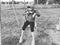 Girl on a swing. Monochrome retro photography. A child in a sports uniform is swinging. In the background is the stadium. Sadness