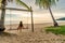 The girl swings on the swing and looks at the sunset on the tropical beach. Freedom, leisure, vacation, concept of