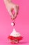 Girl takes cherry from the cake spread with cream. the concept of sexual pleasures. pink background, studio shooting