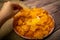 The girl takes a chip from a round dish with potato chips and a saucepan with cheese sauce in the center of the plate. Close up