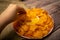 The girl takes a chip from a round dish with potato chips and a saucepan with cheese sauce in the center of the plate. Close up