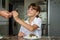 A girl takes a fork from her mother`s hand while preparing to dine at the kitchen table