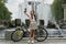 A girl takes a selfie near a Bicycle and a fountain. Long beautiful hair.