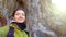 The girl takes a selfie and smiles against the background of beautiful rocks. Winter trip to nature. Warm coat and backpack