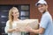 Girl taking a delivery form handsome courier in blue uniform