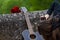 Girl taking photo of guitar and red roses on the old bridge wall