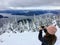 A girl taking a picture atop Cypress Mountain overlooking the ocean below.