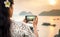 Girl taking seaside sunset picture with smartphone