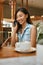 Girl Talking On Phone At Coffee Shop. Woman Having Call On Smartphone At Cafe. Beautiful Asian Model In Casual Clothes