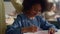 Girl talking with teacher in classroom. Smiling schoolgirl writing in notebook