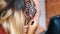 A girl, tattoo master, mehendi artist makes drawing of henna tattoo on scalp of bald Caucasian man, shoulder, neck.The