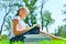 A girl teaches assignments on textbooks and sits on the green grass in the park