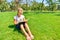 A girl teaches assignments on textbooks and sits on the green grass in the park