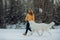 Girl teaches how to right run a dog in winter park. The girl with the Maremma . Forest on background