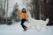 Girl teaches how to right run a dog in winter park. The girl with the Maremma . Forest on background