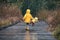 Girl with teddy bear in matching yellow raincoats walking in the