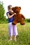 Girl with teddy bear in a meadow